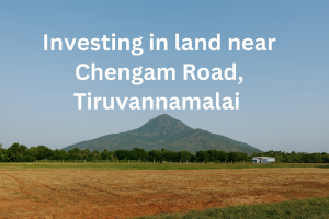 A landscape view of Chengam Road, Tiruvannamalai, showcasing open land with lush greenery and a distant mountain backdrop. The text 'Investing in land near Chengam Road, Tiruvannamalai' is prominently displayed, blending seamlessly with the scenic surroundings.